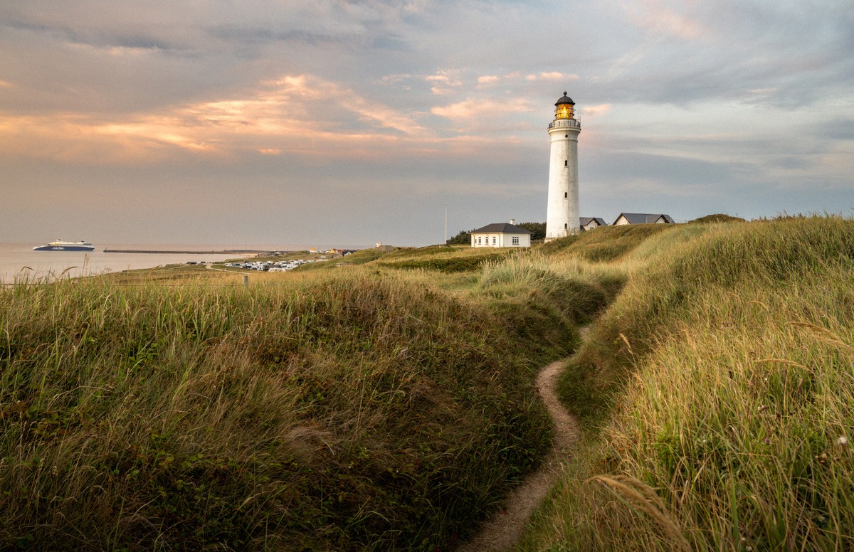 Hirtshals Fyr lighthouse in the dunes, with a ferry on the North Sea in the background